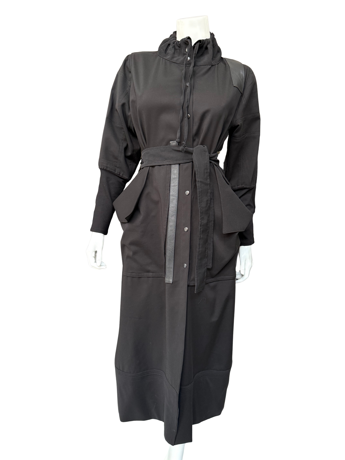 Front view of charcoal gray Mary Jane Jacket on mannequin displaying ruffled collar, snap-front closure, and sophisticated long-line cut with belt