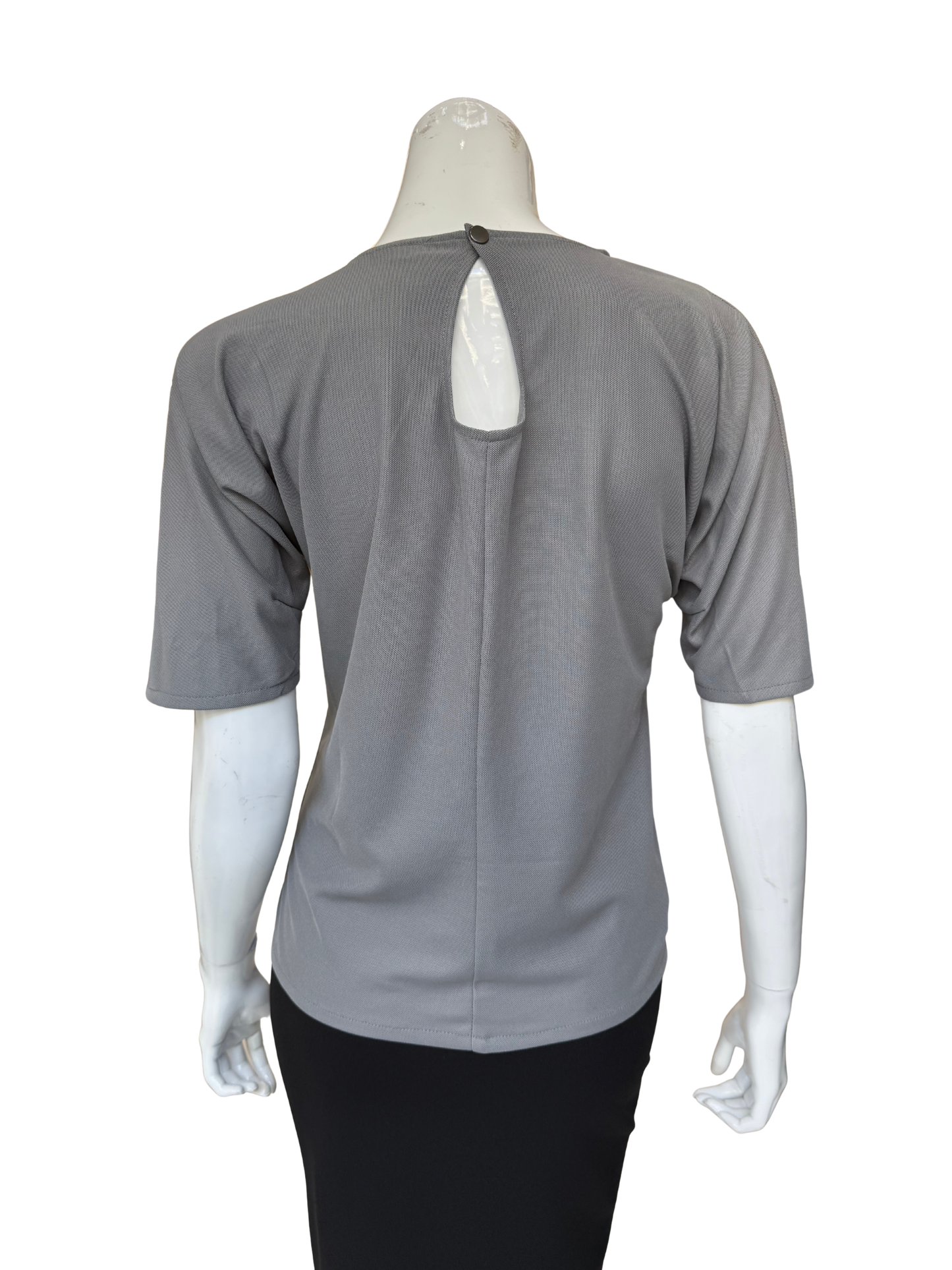 Back view of grey patch top showing keyhole detail and quality construction with sophisticated textured fabric contrasts and contemporary appeal