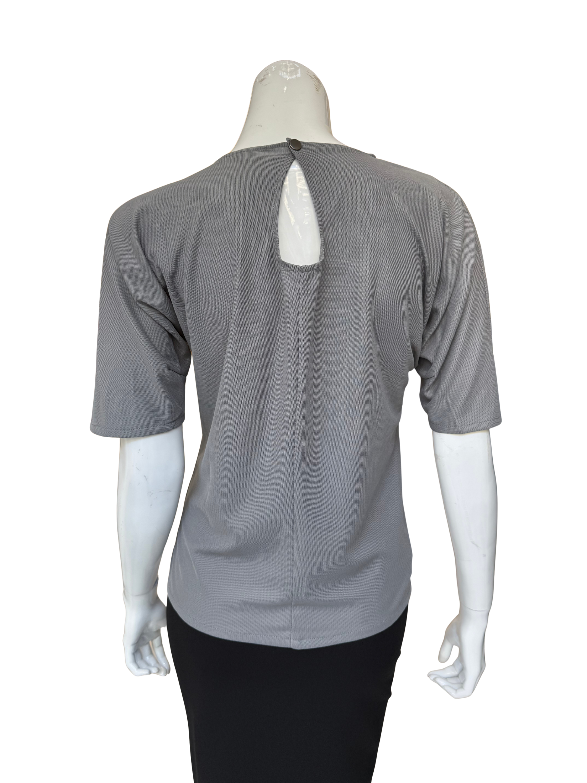 Back view of grey patch top showing keyhole detail and quality construction with sophisticated textured fabric contrasts and contemporary appeal