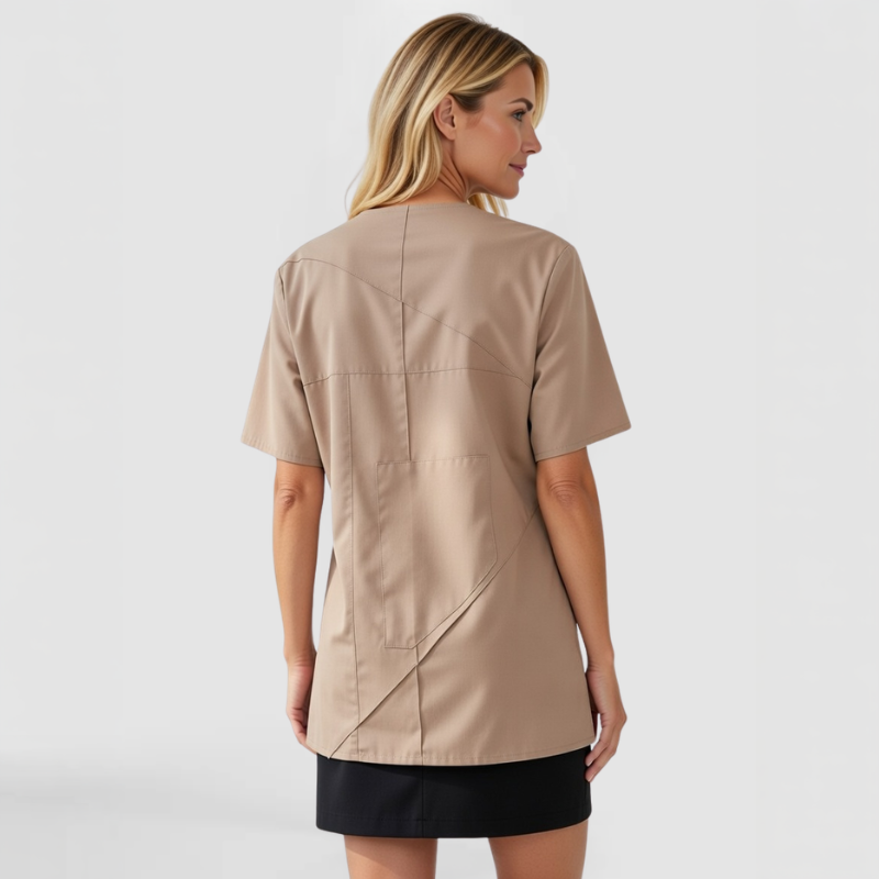 Rear view of model in SWABY Nixxa Top in tan featuring patchwork design with raw-edge stitching across the back; smooth, relaxed silhouette emphasizing soft drape, subtle texture, and modern artistic appeal.