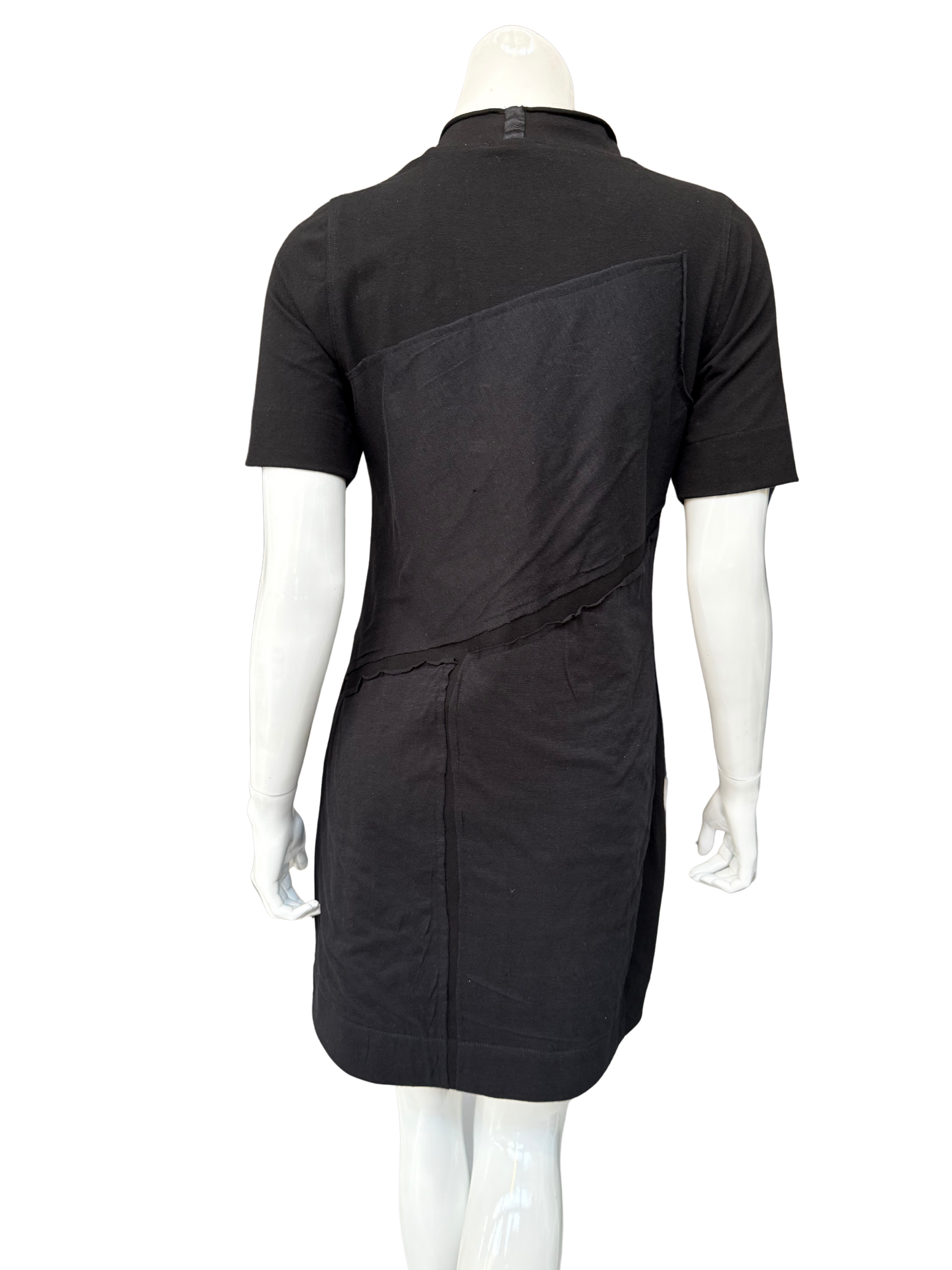 Back view of black DeAnna Dress on mannequin displaying A-line silhouette and asymmetrical raw-edge patch design elements
