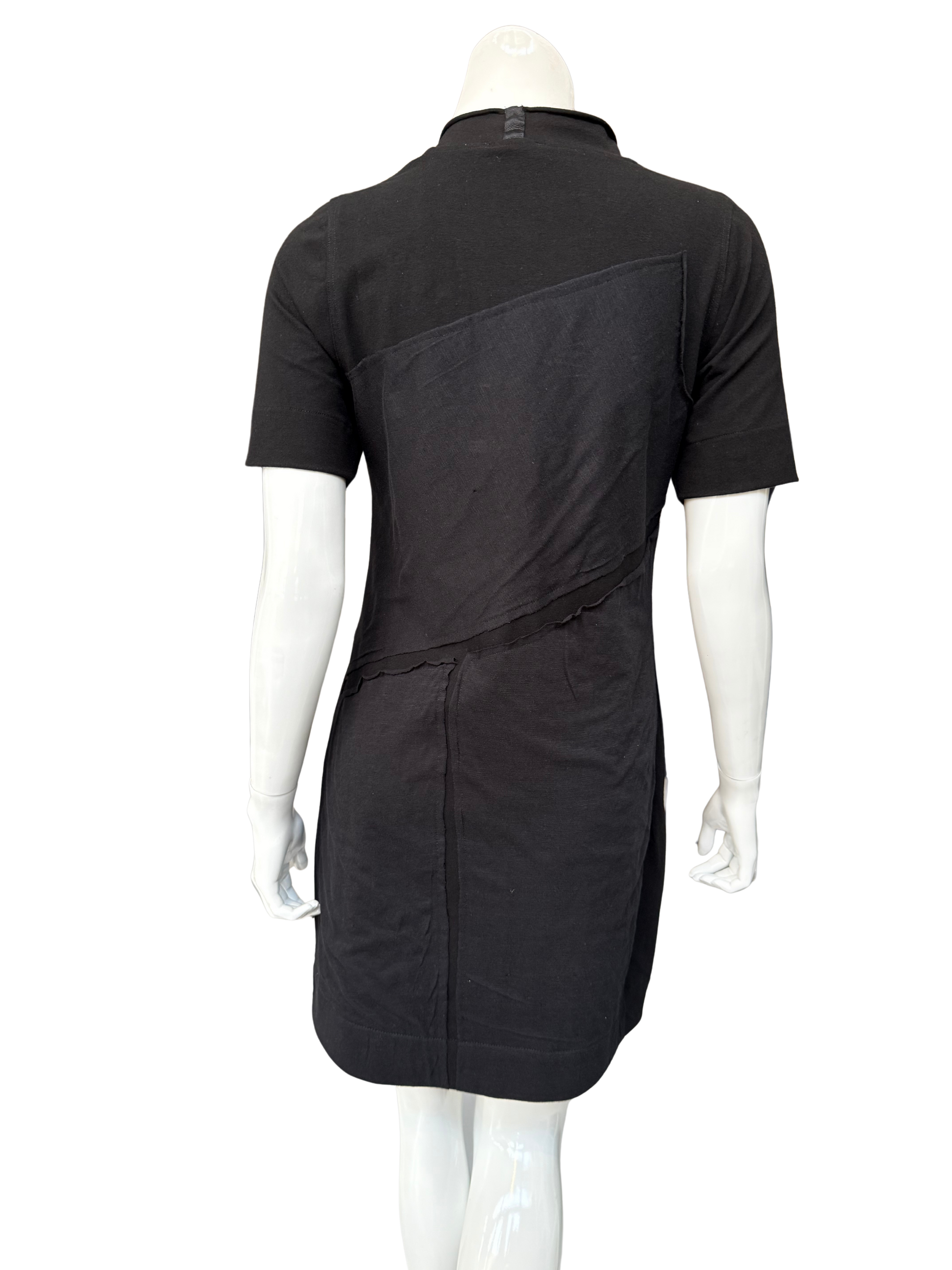 Back view of black DeAnna Dress on mannequin displaying A-line silhouette and asymmetrical raw-edge patch design elements