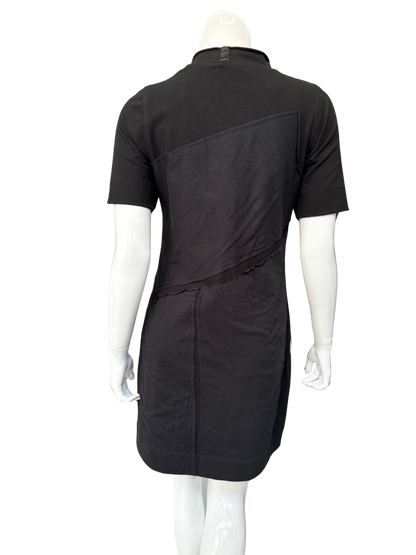 Back view of black DeAnna Dress on mannequin displaying A-line silhouette and asymmetrical raw-edge patch design elements