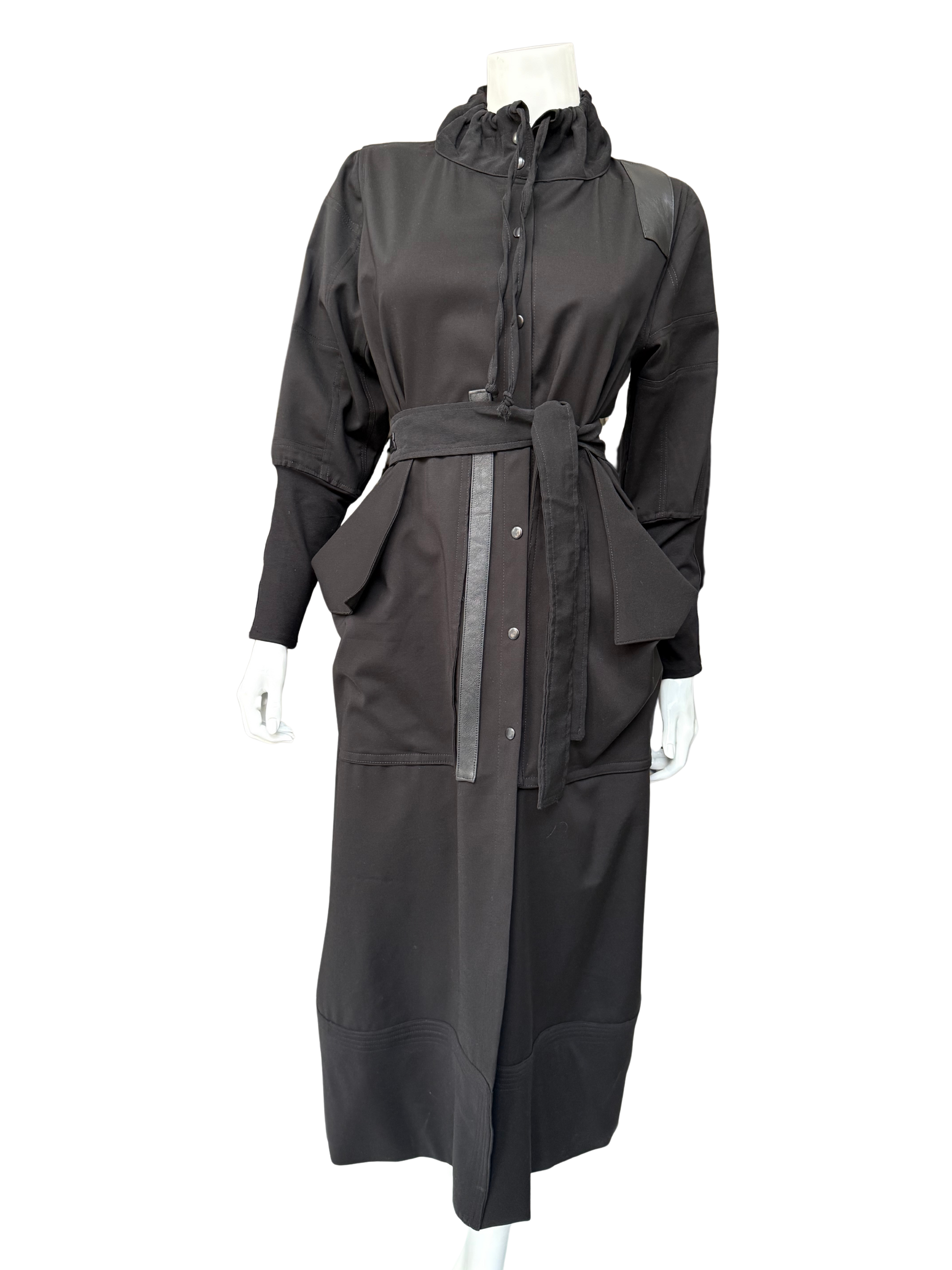 Front view of charcoal gray Mary Jane Jacket on mannequin displaying ruffled collar, snap-front closure, and sophisticated long-line cut with belt