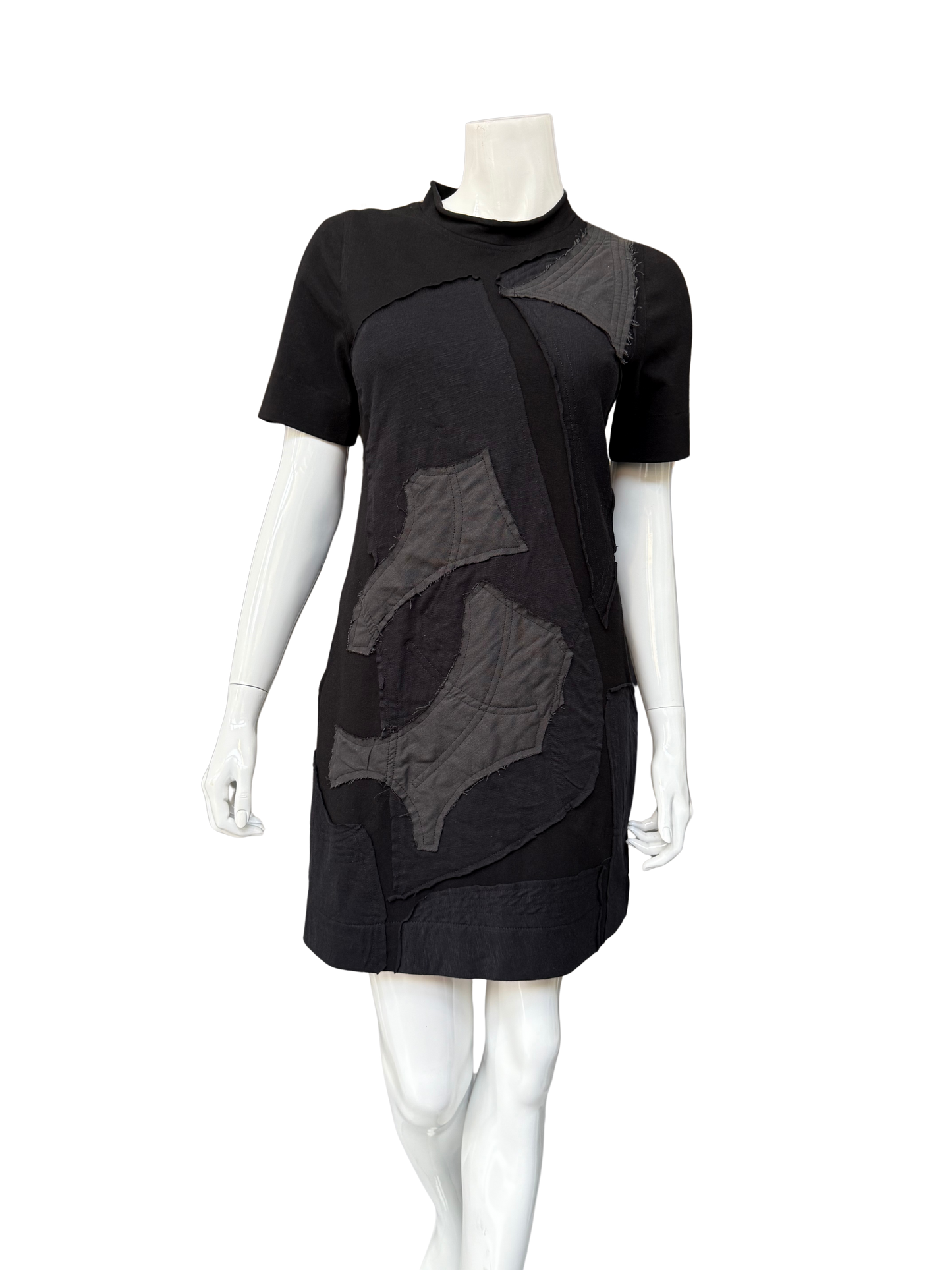 Front view of black DeAnna Dress on mannequin showing complete A-line silhouette with gray patchwork details and functional side pockets