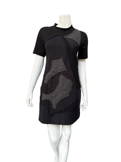 Front view of black DeAnna Dress on mannequin showing complete A-line silhouette with gray patchwork details and functional side pockets