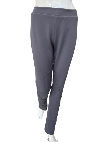Front view of contemporary knit stretch crepe pants in charcoal showing distinctive seaming details and ankle-length silhouette with modern visual interest