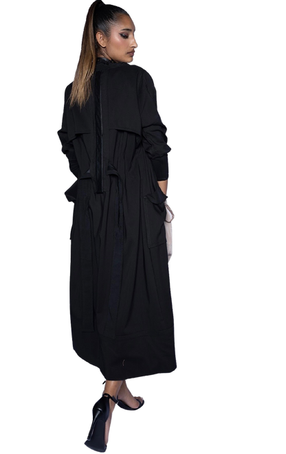 Model wearing black Mary Jane Jacket cinched at waist, showing full-length silhouette and refined trench styling for evening wear