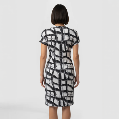 A model poses facing away from the camera in a distinctive  black and white patterned dress, knee-length and short sleeves. Made by SWABY- A New York Fashion Designer.
