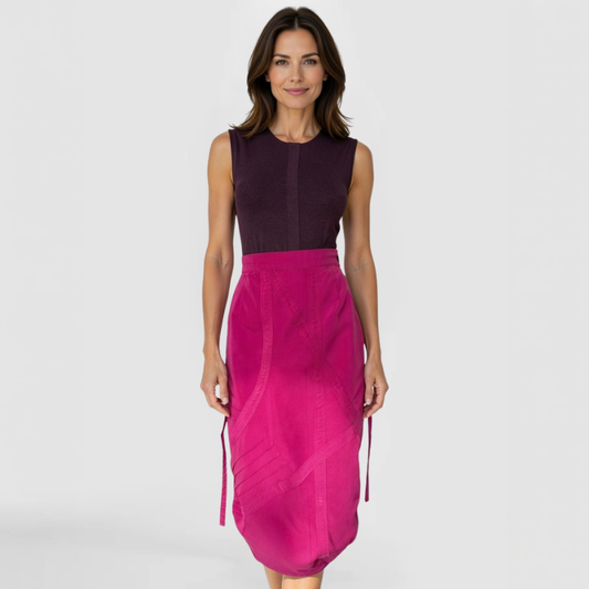 Front view of model wearing SWABY Architect Skirt in fuchsia; high-waisted midi length with angular crisscross seaming, side ties, subtle pockets, and side zipper for wrinkle-resistant comfort and architectural sophistication.