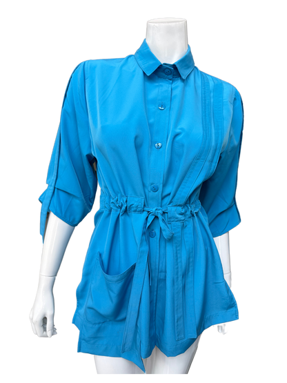 Front view of aqua blue Molli Top on mannequin showing button closure, collar detail, front pockets, and adjustable drawstring waist feature