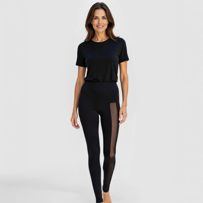 Front view of model in SWABY Shereen Leggings in black with transparent mesh panels along the legs; high-waisted, form-fitting luxury design highlighting soft drape, stretch, and sheer side detailing for refined sophistication.