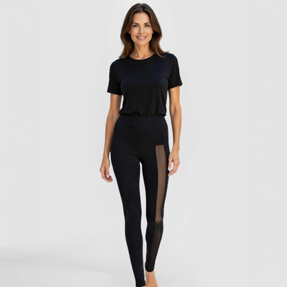 Front view of model in SWABY Shereen Leggings in black with transparent mesh panels along the legs; high-waisted, form-fitting luxury design highlighting soft drape, stretch, and sheer side detailing for refined sophistication.